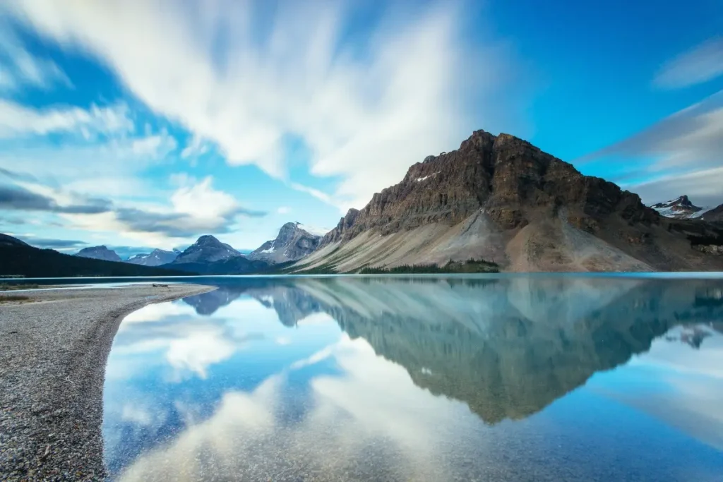 Scenic view of Bow Lake reflecting Crowfoot Mountain and blue sky with clouds along the Icefields Parkway in Banff National Park