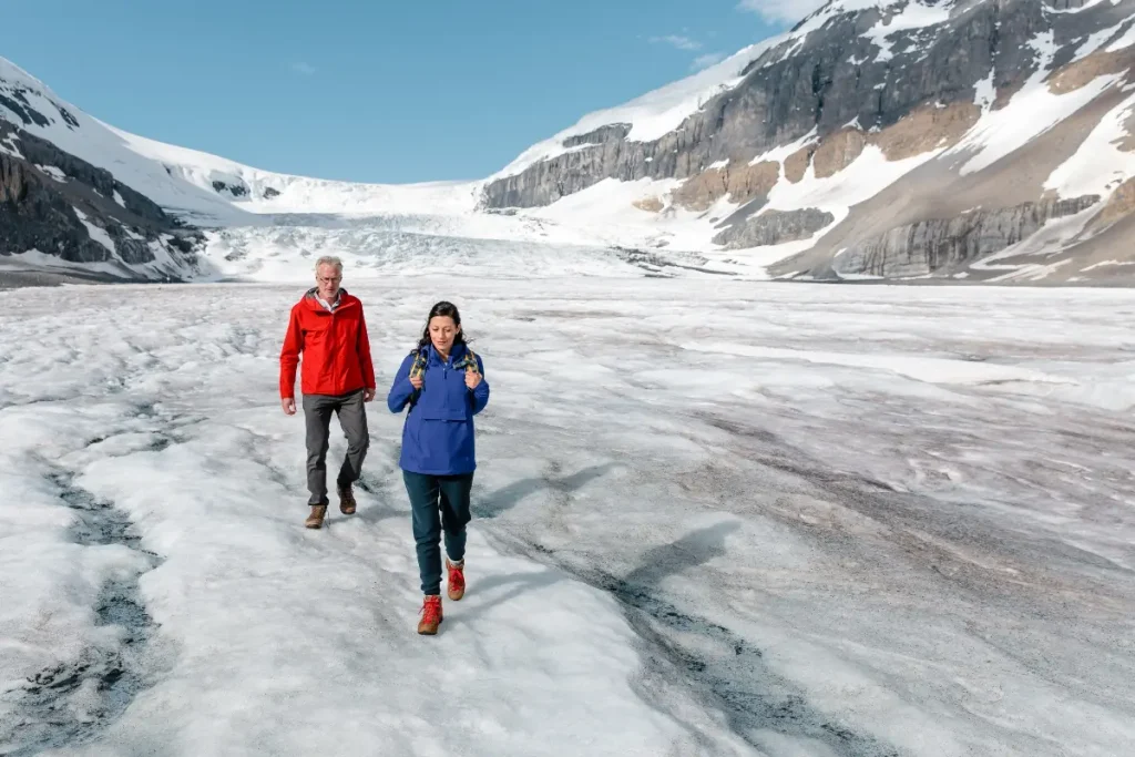 Two hikers on a guided small group walking tour across the Athabasca Glacier along the Icefields Parkway in Jasper National Park