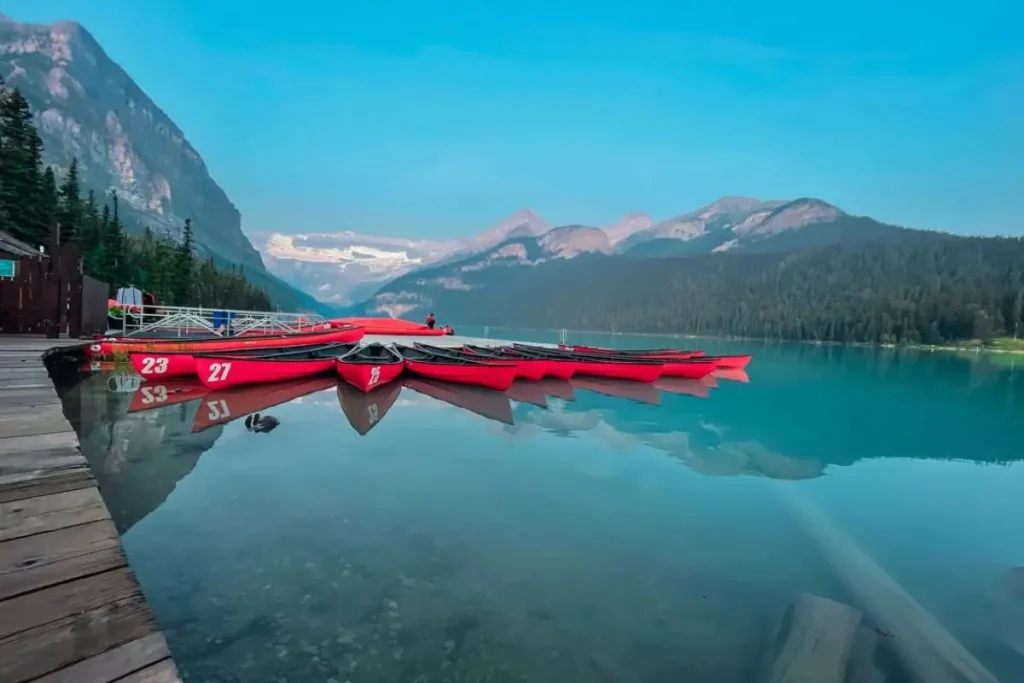 Red canoes docked on the turquoise water at Lake Louise, Canada, surrounded by majestic mountains in Banff National Park