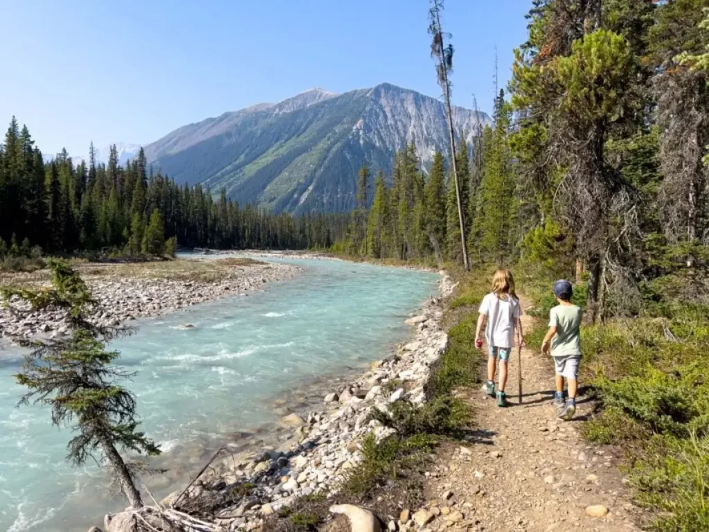 Two kids hiking along a turquoise river in walk marble canyon kootenay national park